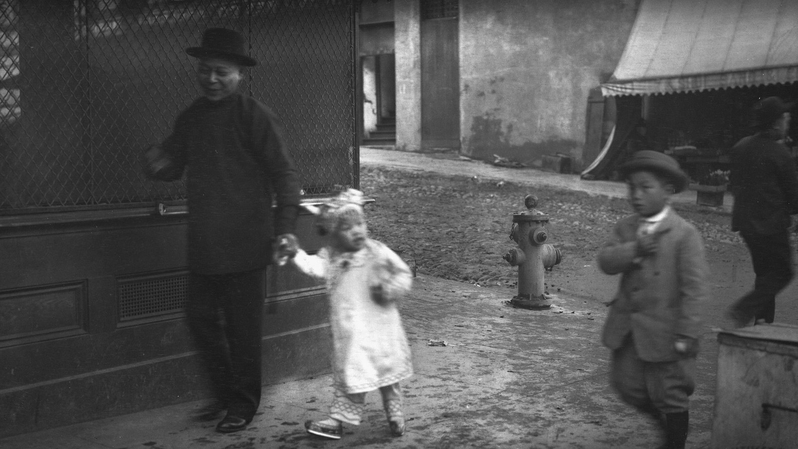 Homme tenant la main d'un jeune enfant sur un trottoir, photographie ancienne en noir et blanc